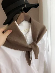 Gros plan d'un foulard triangulaire en maille marron sur une chemise blanche