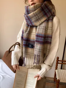 Close-up of thick plaid scarf with long fringe details in soft beige and blue tones