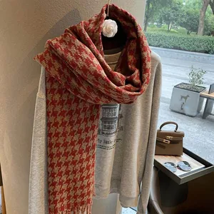 Detail von rot-gelbem Hahnentritt-Schal mit eleganter Fransen-Textur und warmem Winter-Stil