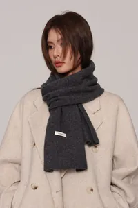 Close-up of a 100% wool scarf texture showing the fabric label on a grey knitted wrap