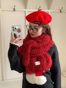 Detail of red plush wool scarf with label and matching beret on a model in winter outfit