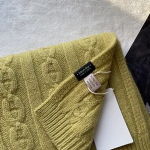 Detail of green 100% pure wool cable knit texture with brand label and washing tag