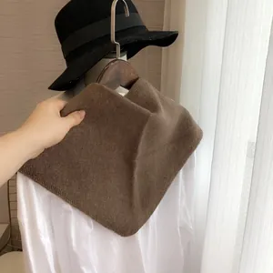 Détail d'une écharpe triangulaire en tricot marron doux sur une chemise blanche