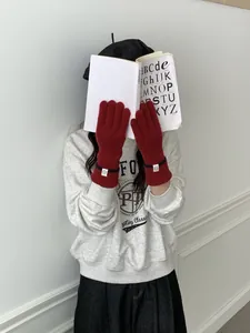 Détail de gants en maille rouge avec poignets côtelés et écusson smiley rond