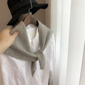 Détail du foulard triangulaire en maille grise avec l'étiquette de marque Modeng Mi