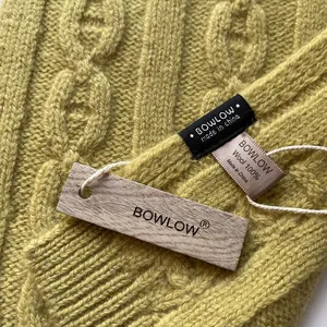 Macro shot of 100% pure wool yellow cable knit scarf with brand labels and textured weave