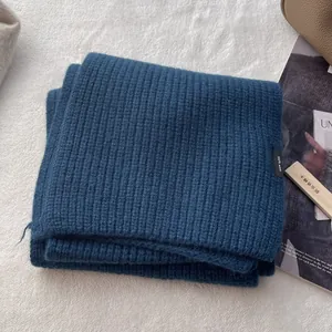 Detailansicht des dunkelblauen Strickschals aus 100% Wolle mit Textur und Etikett