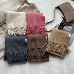 Close-up of five colorful 100% pure wool scarves with fringe edges and woven labels
