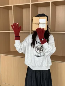 Détail de gants en tricot rouge foncé avec ouverture tactile et rayures au poignet
