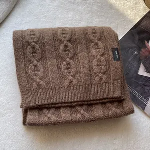 Close-up of 100% wool knit scarf in dark coffee showing detailed cable knit pattern