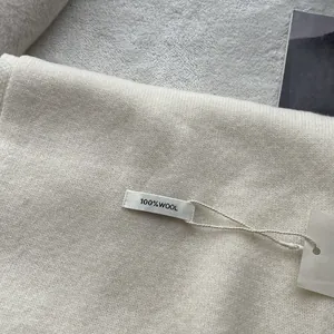 Detail shot of 100% pure wool scarf texture with material label and tag on soft fabric