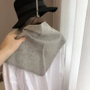 Gros plan sur la texture du foulard triangle en tricot gris doux et bordure nette