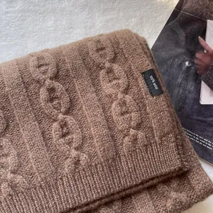 Detail view of 100% pure wool scarf with knitted chain pattern and fabric label