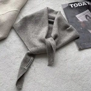Détail de la texture d'un foulard triangle gris en tricot de laine avec étiquette