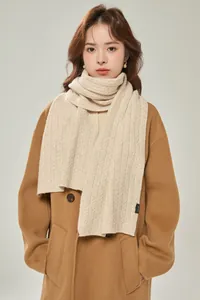 Dettaglio macro della sciarpa beige in 100% lana con classica trama a maglia a treccia