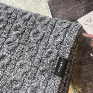 Macro shot of grey cable knit texture on a 100% pure wool scarf showing detailed fibers