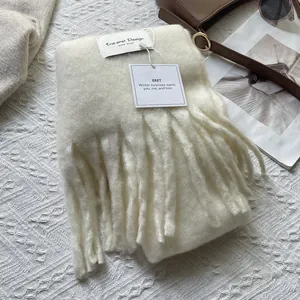 Detailed texture of off-white knitted scarf with tassels and elegant brand labeling