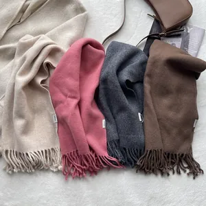 Detailed texture of thick pure wool scarves with tassels in beige, pink, grey and brown