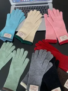 Guanti in maglia colorati con polsini a contrasto su un tavolo nero con laptop