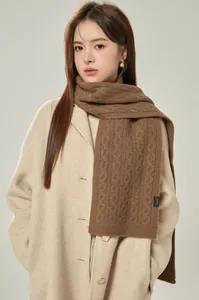 Detail of premium brown cable-knit 100% wool scarf showing texture and quality label