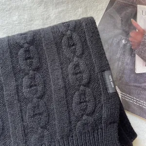 Detailed close-up of premium black 100% pure wool scarf with thick cable knit texture