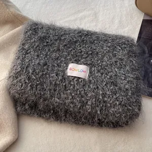Close-up of soft grey plush scarf material with a colorful BOWLOW woven brand label