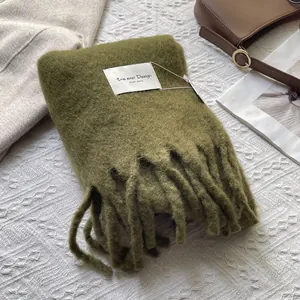 Close-up of olive green mohair scarf texture with chunky tassels and artisanal tag