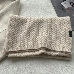 Dettaglio dell'etichetta 100% pura lana su una sciarpa invernale a maglia intrecciata