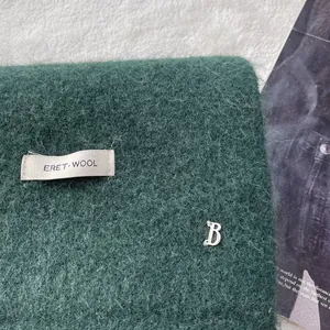 Detail of dark green wool scarf showing long plush texture and metallic B hardware detail