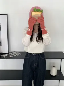Détail de gants tricotés rose corail avec poignets côtelés et écusson logo circulaire