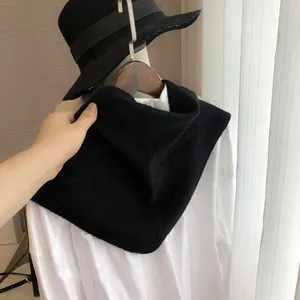 Détail d'un tour de cou noir en maille de laine avec une chemise et un chapeau