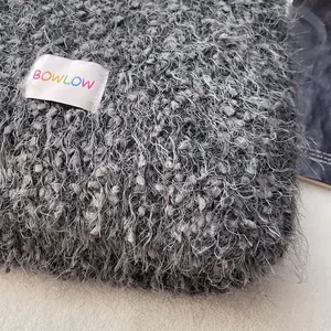 Close-up of fluffy grey wool scarf with BOWLOW brand label and soft plush texture