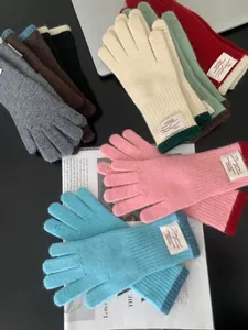 Guanti in maglia colorati con etichette Bonjour e polsini a costine su un tavolo