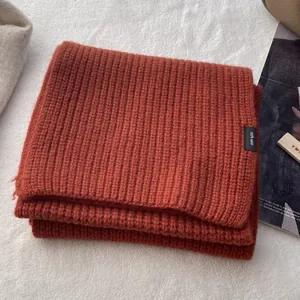 Detailansicht des Etiketts aus 100 % reiner Wolle auf einem rostroten Strickschal