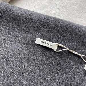 Macro shot of 100% Australian wool fabric texture and material label on dark gray scarf