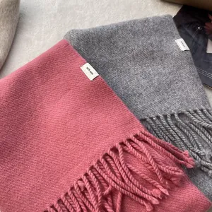 Macro detail of 100% pure wool scarves with tassels in rose and charcoal grey colors