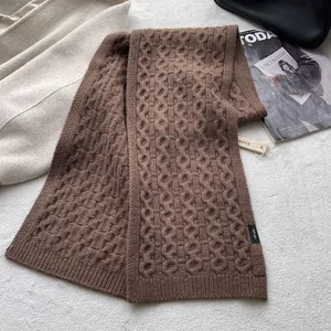 Macro detail of brown chunky knit wool scarf featuring 100% wool label and soft texture