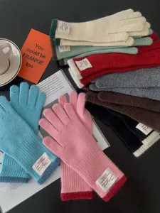 Dettaglio di guanti in maglia colorati con etichette Bonjour in varie tonalità vivaci