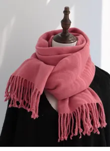 Detail view of pink wool scarf texture and long tassels draped on a mannequin
