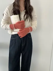 Détail de gants en cachemire tricotés orange avec poignets côtelés et petite étiquette