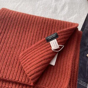 Nahaufnahme des Schals aus 100% Wolle in Karamell mit Rippstrickmuster und Pflegeetikett