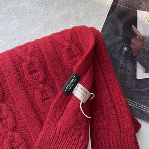 Close-up of red cable knit wool scarf with 100% wool label and brand tag details