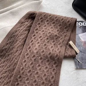 Detail of wool knit scarf texture with thick cable pattern and cedar wood tag