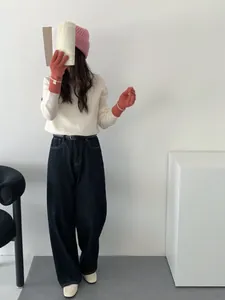 Gros plan de gants en maille rose assortis à un pull crème et un pantalon en jean bleu