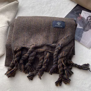 Détail d'une écharpe pied-de-poule caramel et marine avec de longs pompons et étiquette