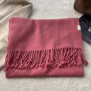 Detail of rose pink 100% wool scarf featuring a woven fabric texture and long fringe edge
