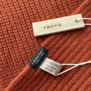 Makroaufnahme der Strickstruktur aus 100% Wolle mit Echtheitsetikett und Holzanhänger