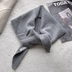 Vue détaillée du foulard triangulaire en maille grise avec étiquette de marque
