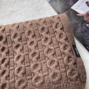 Detail view of 100% wool knitted scarf with cable knit texture and premium brand label