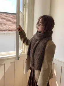 Detail view of a thick dark brown plush scarf styled with an oatmeal wool coat and skirt